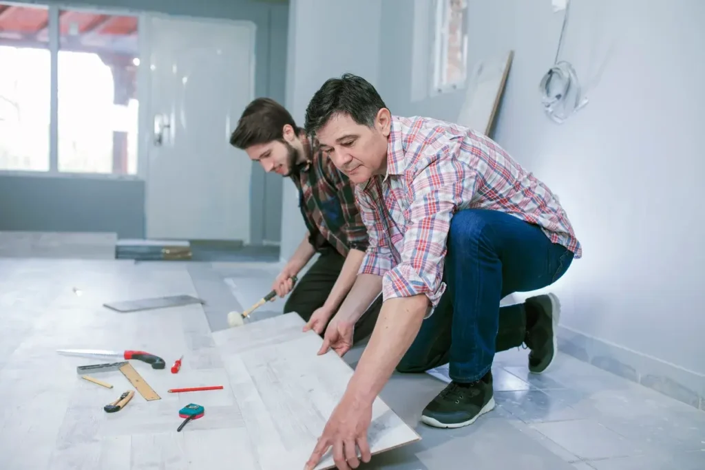 Des hommes installent un nouveau sol en bois stratifié