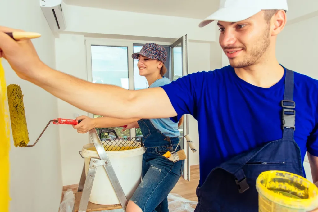 Deux artisans professionnels en train de refaire la peinture des murs intérieurs d'une maison à rénover à Paimpol