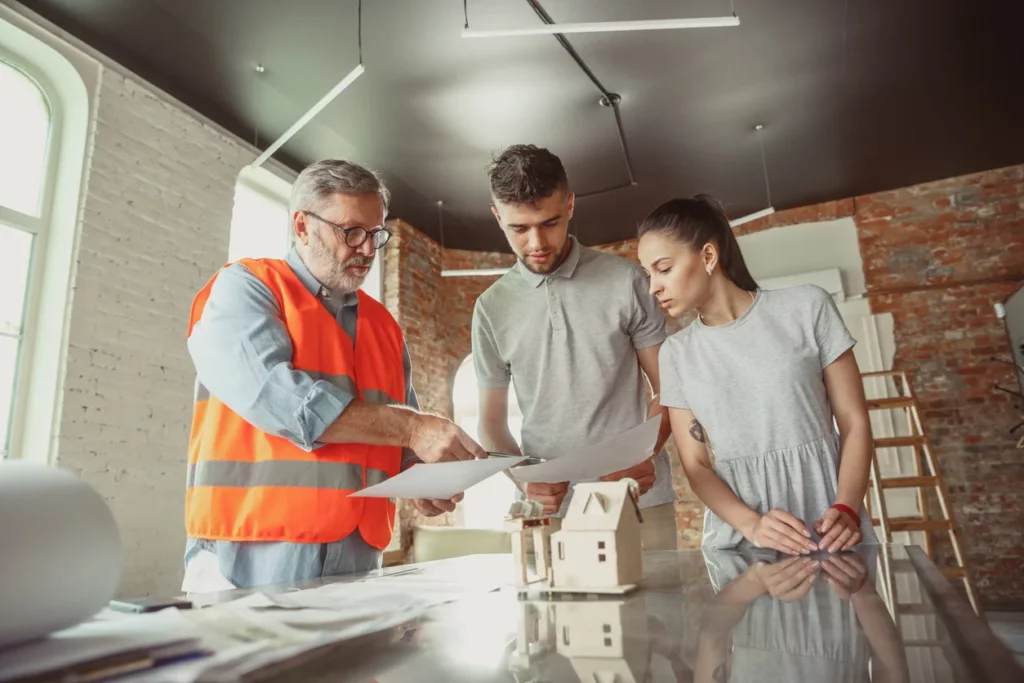 Un architecte qui discute du prix rénovation m2 d’une maison avec un jeune couple de propriétaire