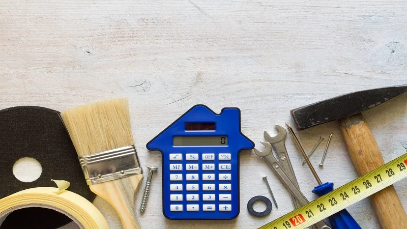 Le coût de rénovation d’une maison, avec une calculatrice en forme de maison entourée d’outils de bricolage, symbolisant l’estimation budgétaire et la planification des travaux.