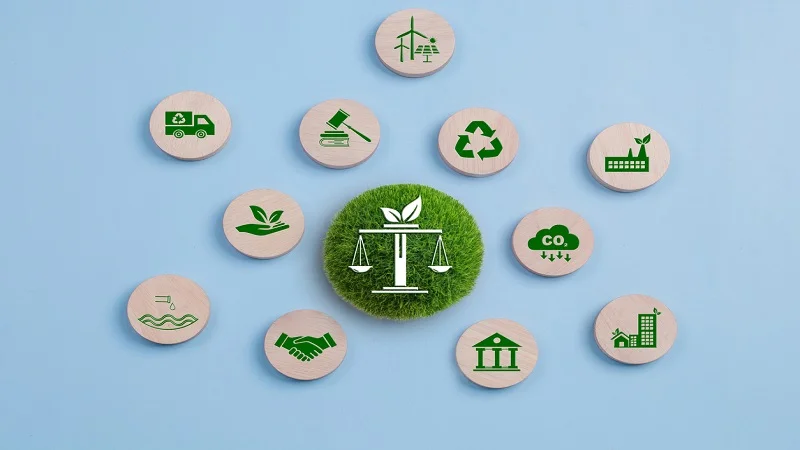 Un concept de réglementations et normes énergétiques, illustré par un symbole de balance verte sur un fond herbeux, entouré d’icônes liées au développement durable, aux énergies renouvelables, au recyclage et à la réduction des émissions de CO2.