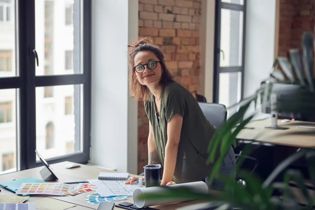 Une architecte d'intérieure se tenant devant son bureau. L'expert qu'il faut contacter pour rénover sa maison.