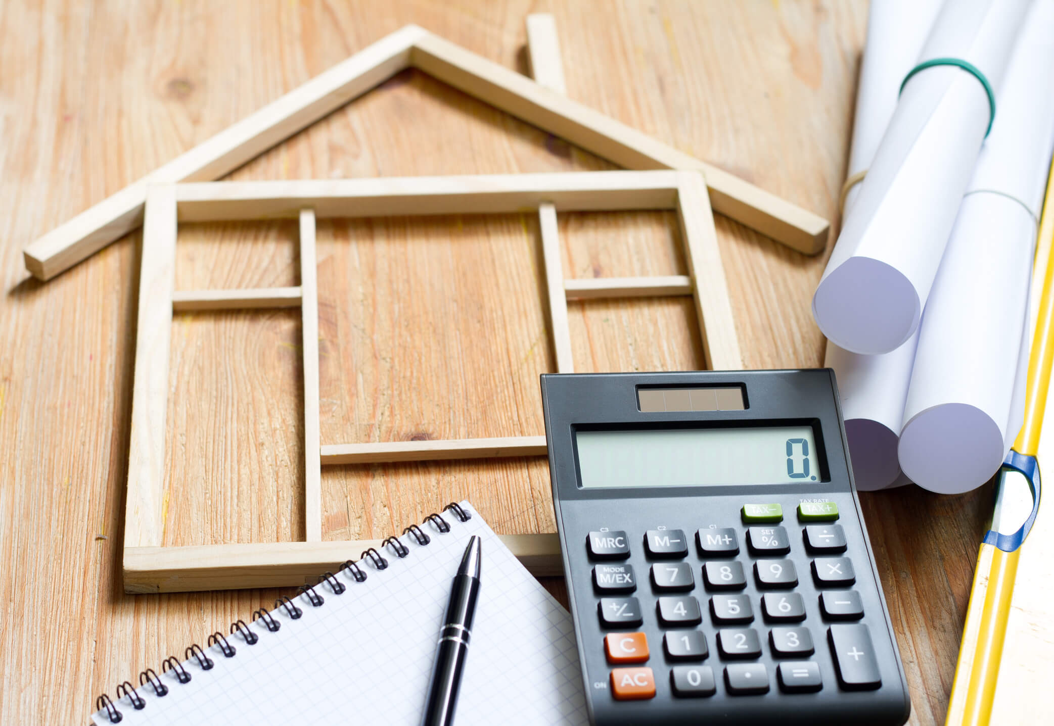 une maquette de maison en bois et une machine pour calculer le coût rénovation maison m2