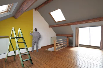 Un professionnel en train de peindre les murs intérieurs d'une maison à rénover