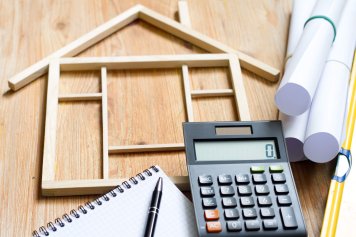 une maquette de maison en bois et une machine pour calculer le coût rénovation maison m2