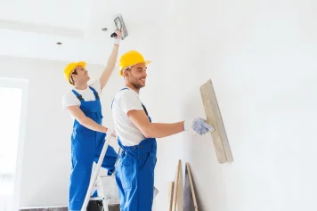 Deux artisans professionnels en train de refaire la peinture des murs intérieurs d'une maison à rénover à Paimpol