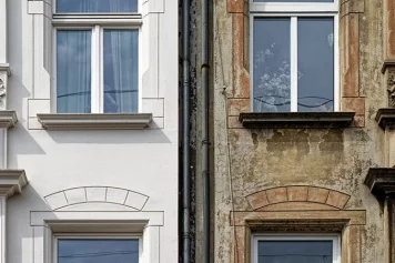 Deux façades de maisons mitoyennes contrastées : l'une rénovée avec une finition impeccable et lumineuse, l'autre présentant des signes d'usure et de vieillissement, symbolisant le potentiel d'un projet de rénovation