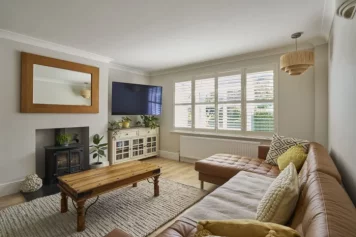 Salon lumineux au style naturel et chaleureux conçu par un architecte à Meudon, avec canapé en cuir et éléments bois